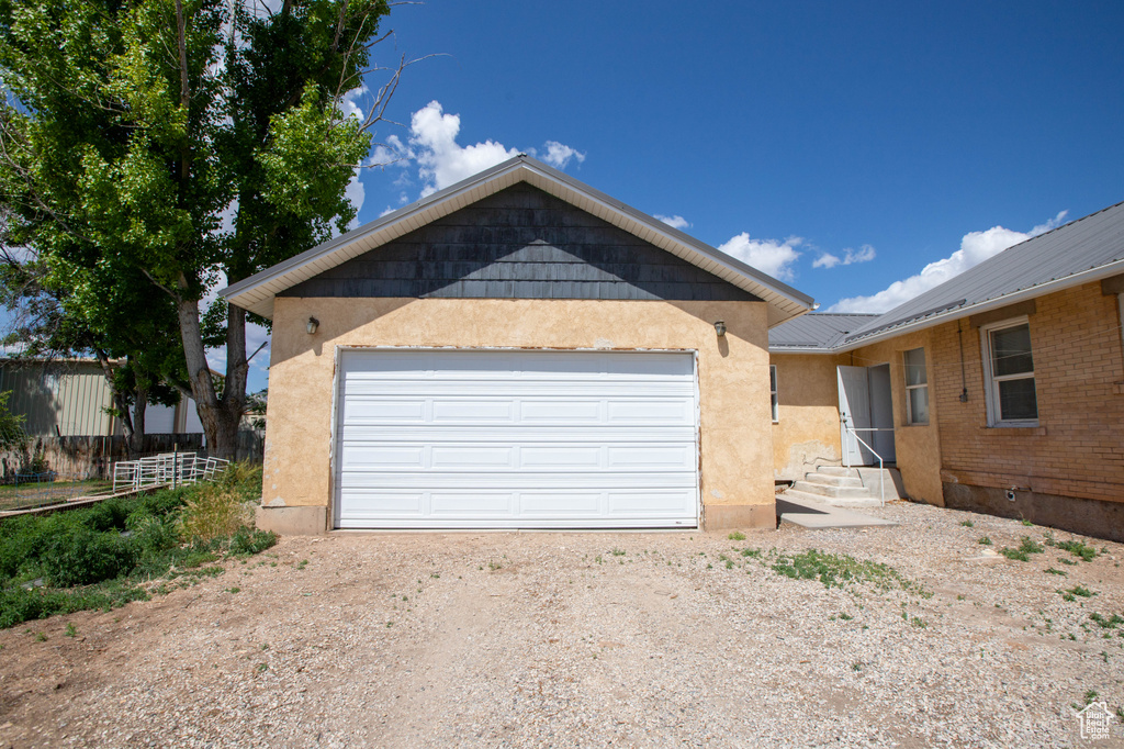 View of front of house with driveway, stucco siding, an attached garage, and metal roof