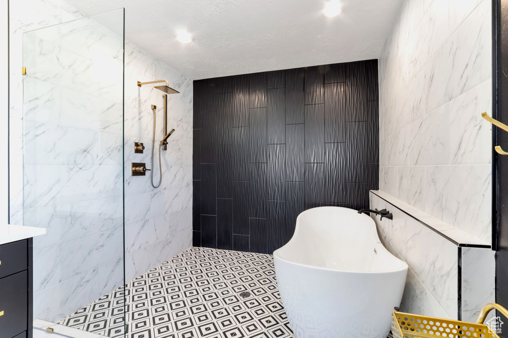 Full bathroom featuring tile walls, a soaking tub, tiled shower, and vanity