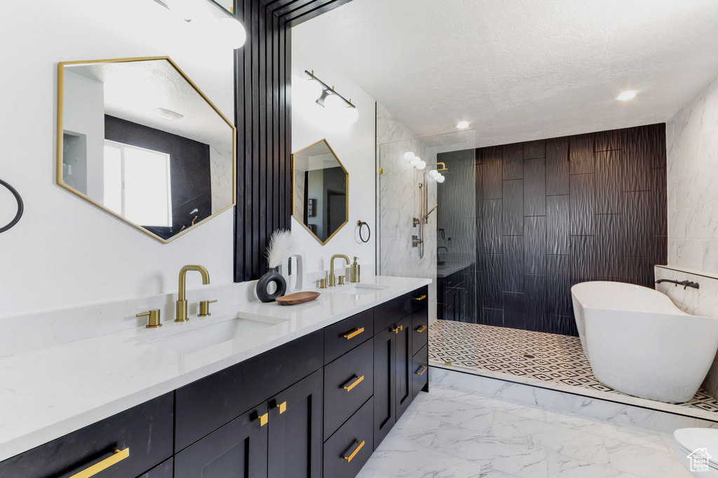 Bathroom with walk in shower, marble look tiles, double vanity, a freestanding bath, and a textured ceiling