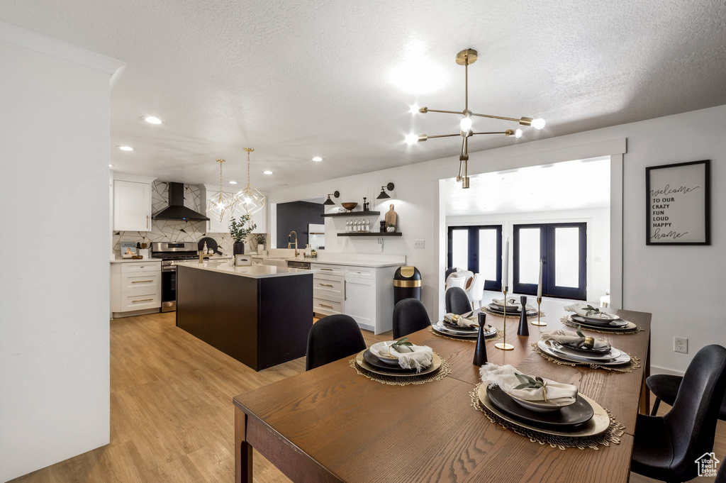 Dining area with light wood-style flooring, recessed lighting, a textured ceiling, and french doors