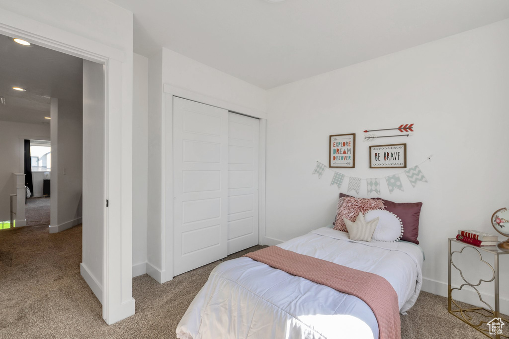 Bedroom with light colored carpet, a closet, and baseboards