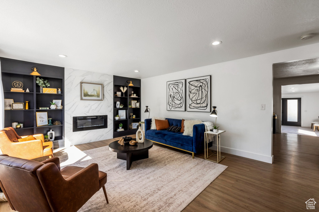 Living area featuring wood finished floors, a high end fireplace, built in features, baseboards, and recessed lighting