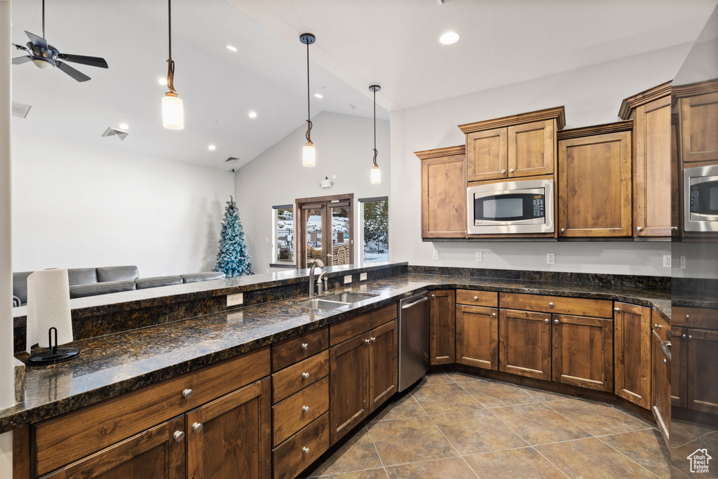 Kitchen with stainless steel appliances, a sink, ceiling fan, hanging light fixtures, and high vaulted ceiling