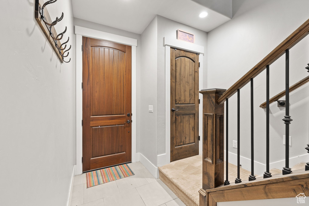 Foyer with baseboards, stairs, recessed lighting, and light tile patterned floors