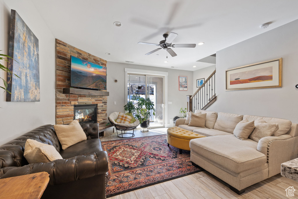 Living area featuring a ceiling fan, stairs, wood finished floors, a fireplace, and recessed lighting