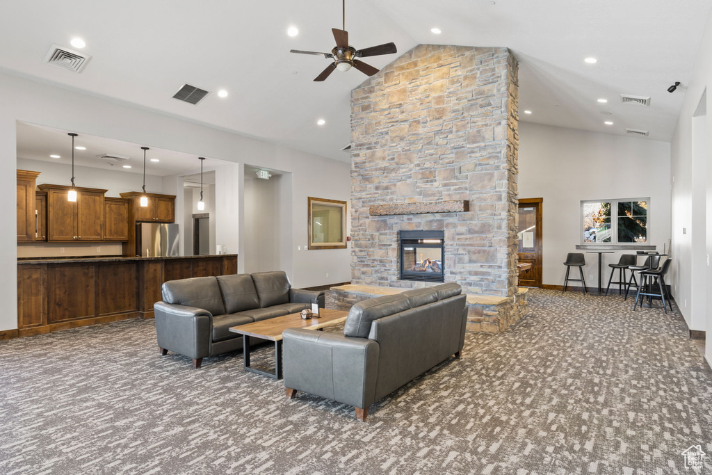 Carpeted living room with high vaulted ceiling, ceiling fan, a stone fireplace, recessed lighting, and baseboards