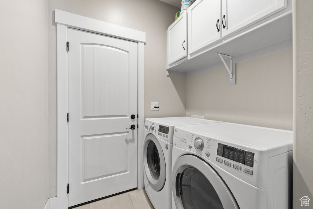 Laundry area featuring independent washer and dryer, cabinet space, and light tile patterned floors