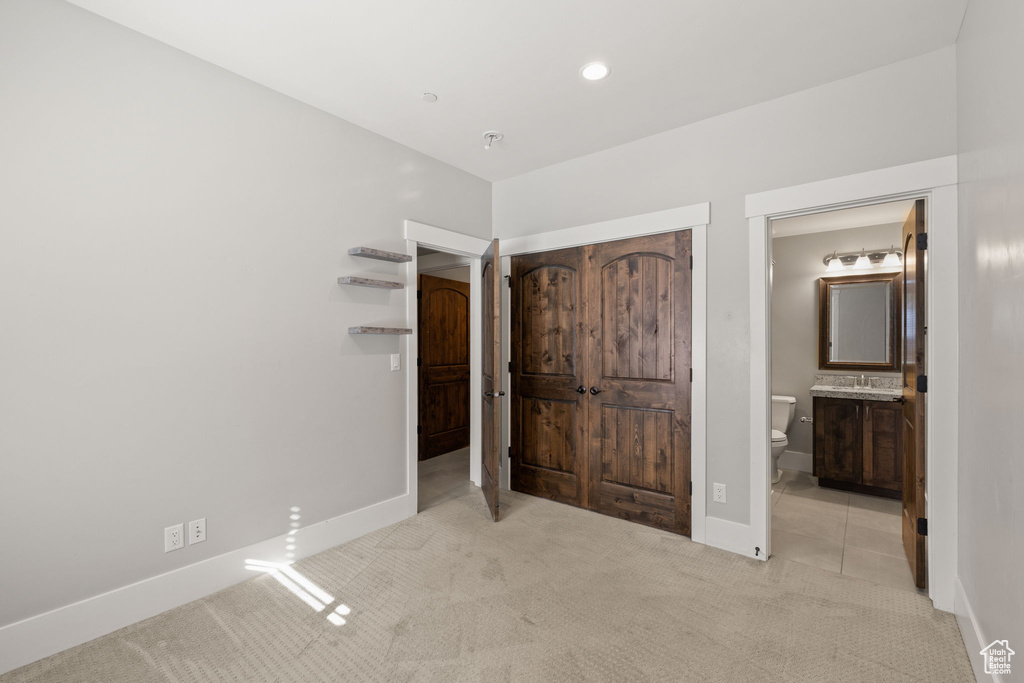 Unfurnished bedroom featuring light colored carpet, baseboards, recessed lighting, and connected bathroom