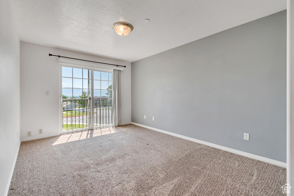 Unfurnished room with carpet flooring, baseboards, and a textured ceiling