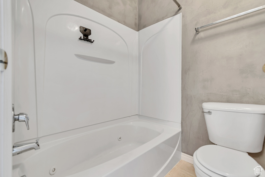 Full bath featuring toilet, a combined bath / shower with jetted tub, and baseboards