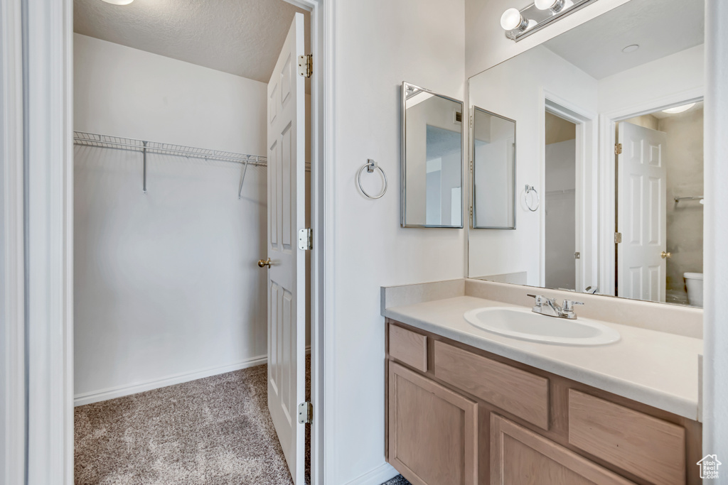 Bathroom with vanity, toilet, baseboards, and a spacious closet