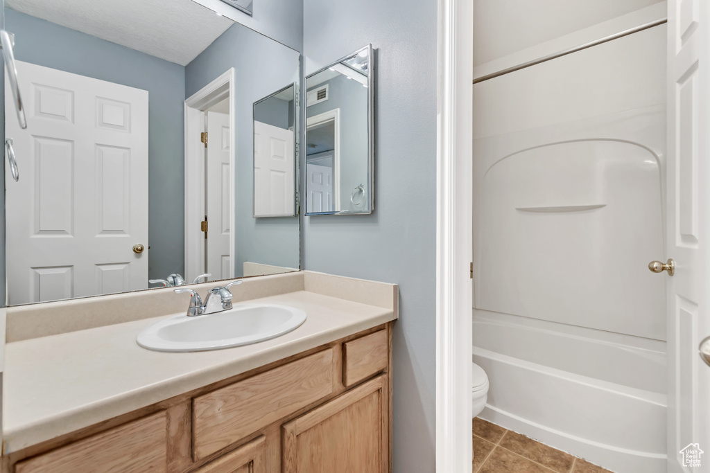 Full bath featuring vanity, toilet, tile patterned floors, and tub / shower combination