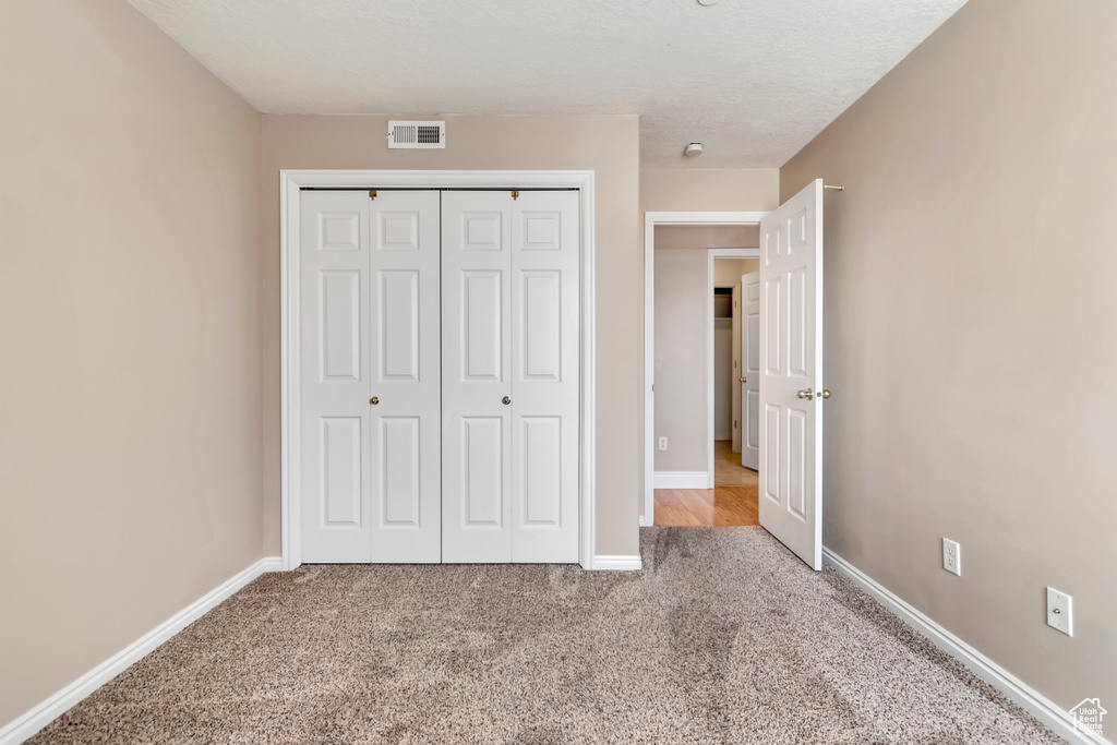 Unfurnished bedroom with carpet, a closet, and baseboards