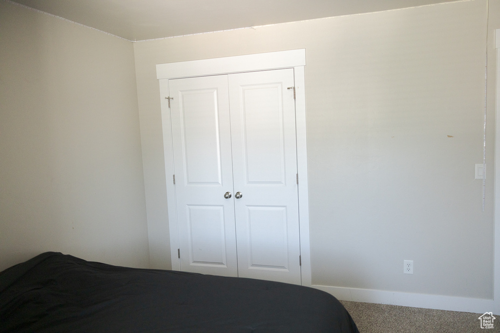 Carpeted bedroom featuring a closet and baseboards