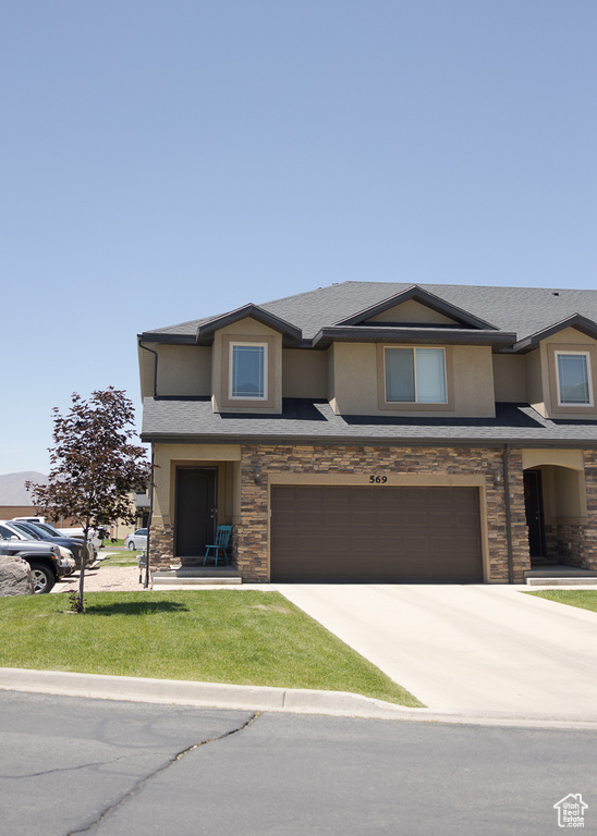 View of front of home featuring stone siding, an attached garage, driveway, and stucco siding