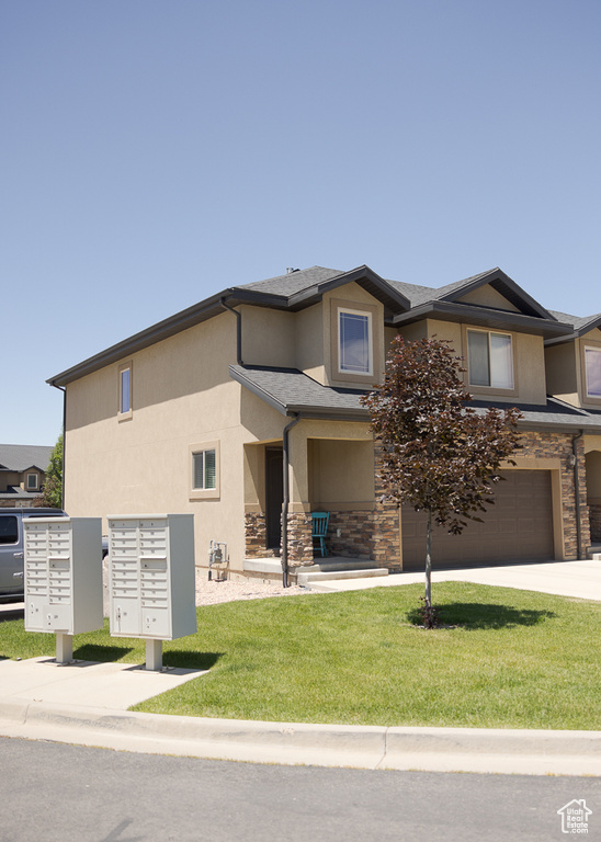 View of front of property featuring stucco siding, stone siding, a garage, and a front lawn