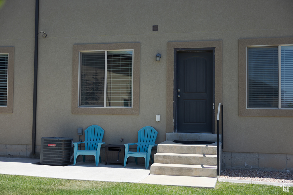 Doorway to property featuring central AC unit, a patio area, and stucco siding
