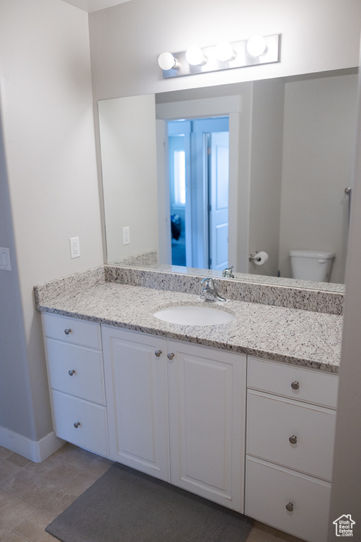 Bathroom featuring vanity, baseboards, toilet, and tile patterned floors