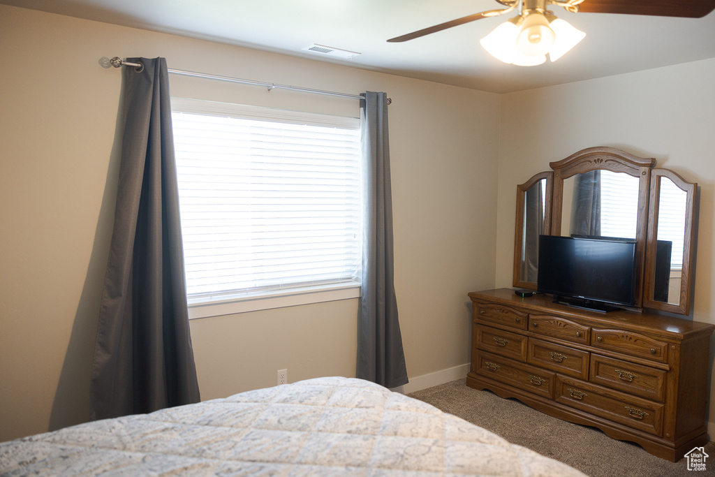 Bedroom featuring light carpet, multiple windows, a ceiling fan, and baseboards