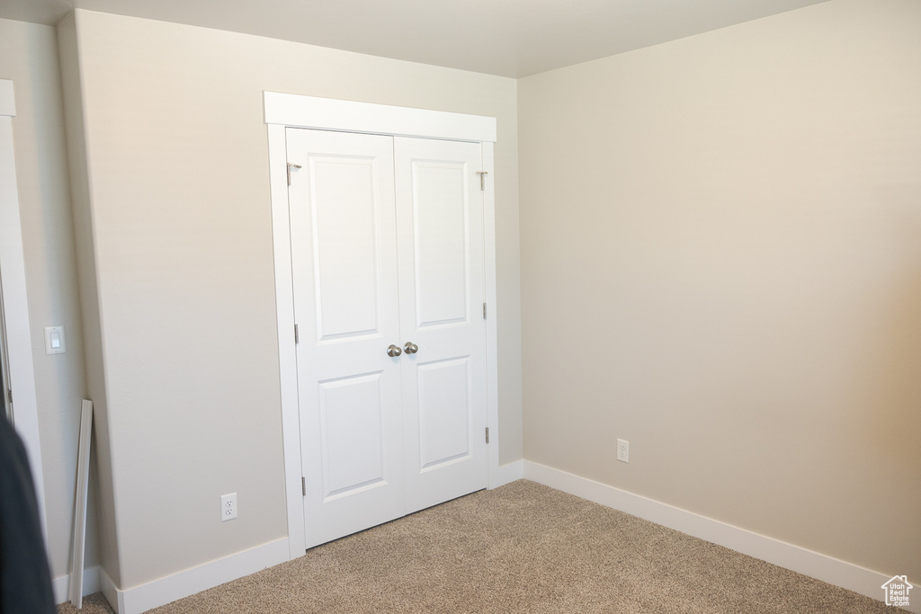 Unfurnished bedroom featuring light carpet, baseboards, and a closet
