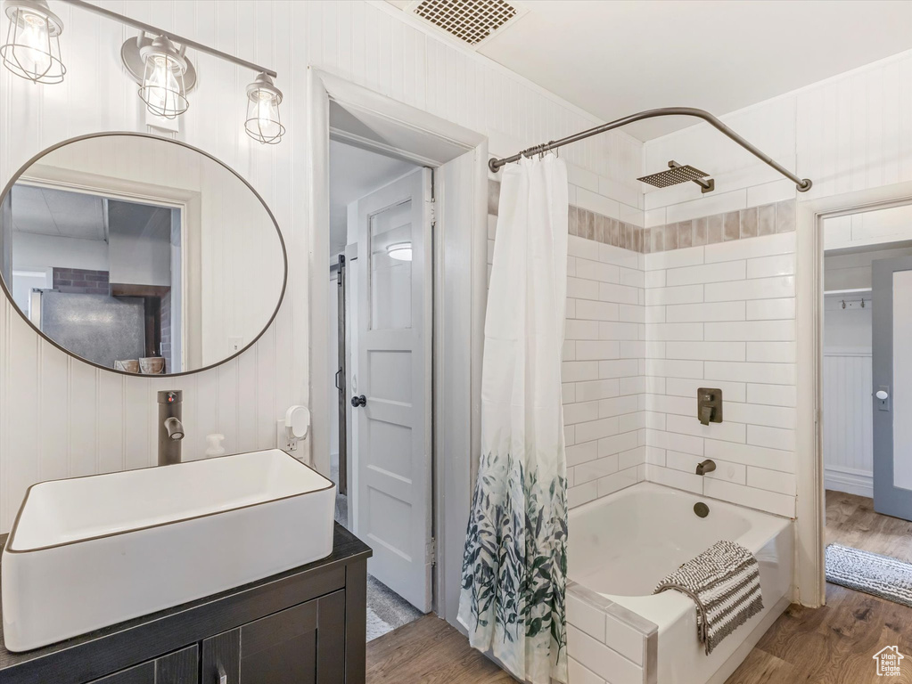 Bathroom featuring shower / bathtub combination with curtain, wood finished floors, and vanity