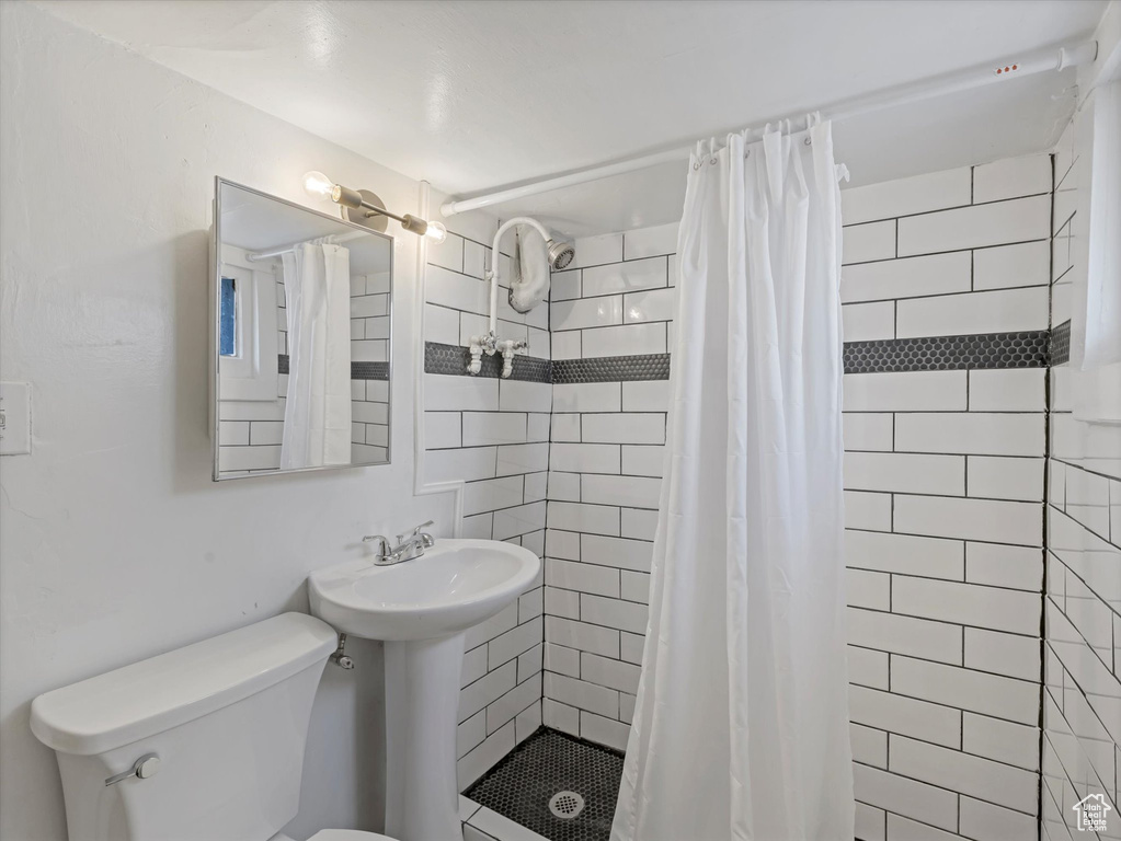Full bath with toilet, a stall shower, and a sink