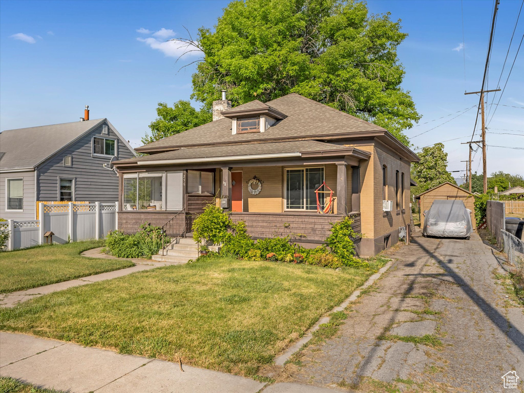 Bungalow-style house featuring asphalt driveway, a shingled roof, a porch, and brick siding