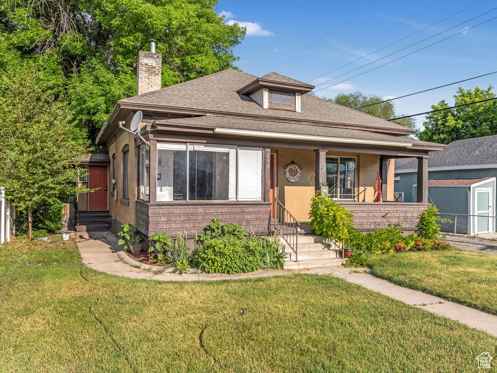 Bungalow with entry steps, a chimney, a shingled roof, and a porch