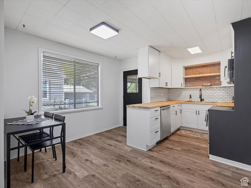 Kitchen featuring butcher block countertops, appliances with stainless steel finishes, a sink, tasteful backsplash, and open shelves