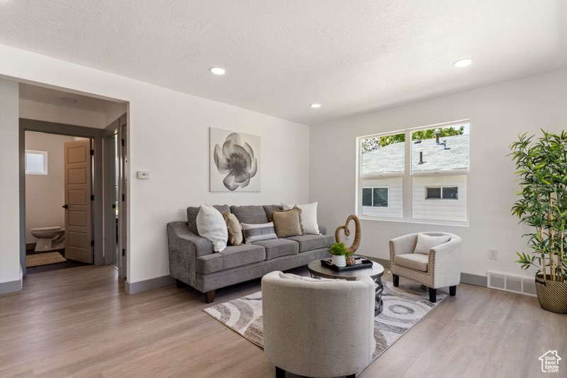 Living room with light wood finished floors, recessed lighting, and baseboards