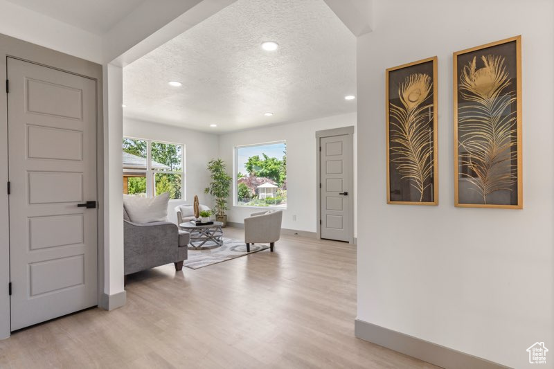Foyer entrance with a textured ceiling, baseboards, recessed lighting, and light wood-style flooring