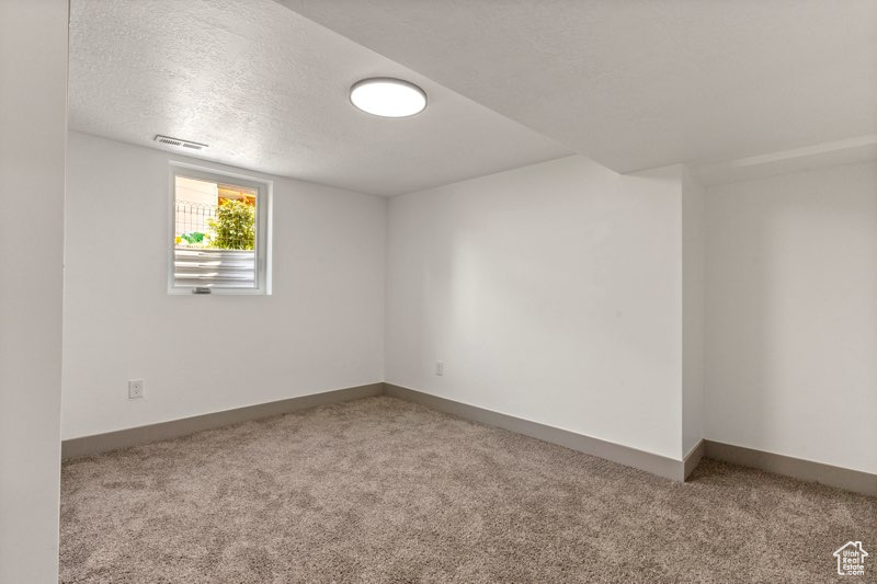 Unfurnished room with carpet floors, a textured ceiling, and baseboards