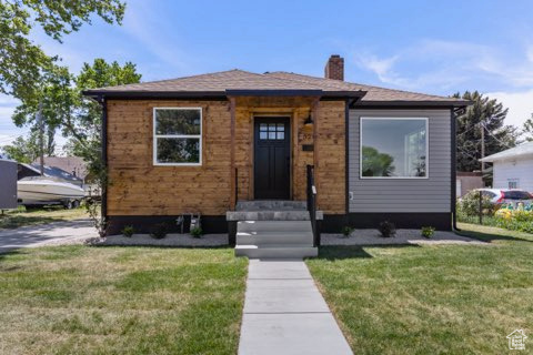 Bungalow-style house with a chimney and a front lawn