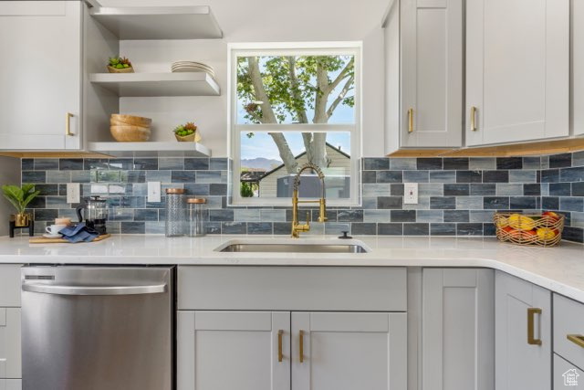 Kitchen featuring dishwasher, a sink, tasteful backsplash, light countertops, and gray cabinets