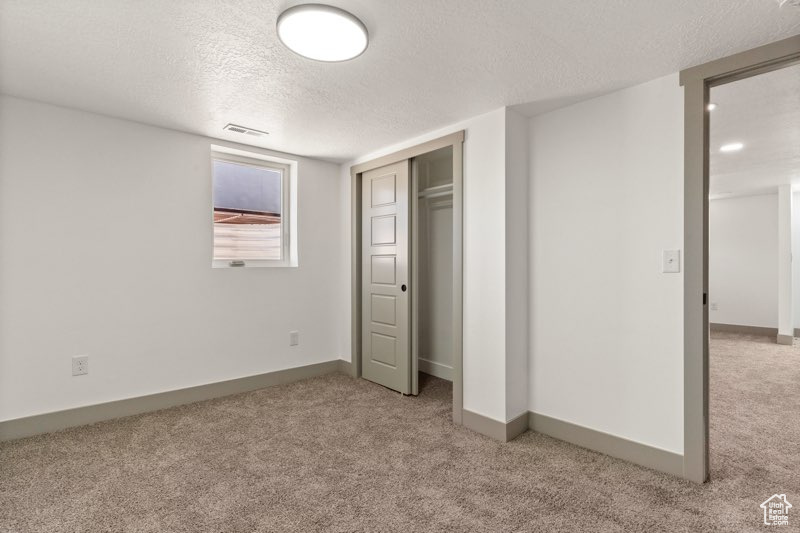 Unfurnished bedroom featuring carpet, a textured ceiling, a closet, and baseboards