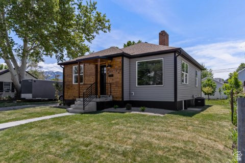 View of front of house featuring a front yard, a chimney, and central air condition unit