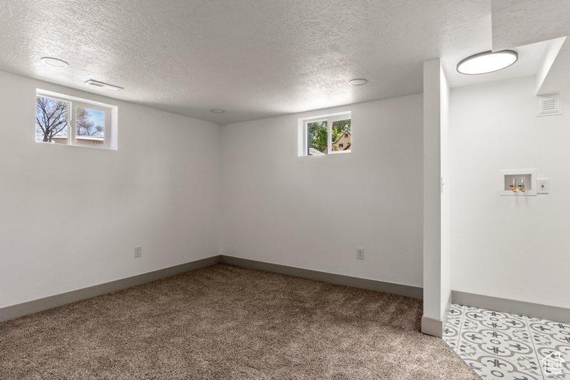 Below grade area with carpet, a textured ceiling, and baseboards