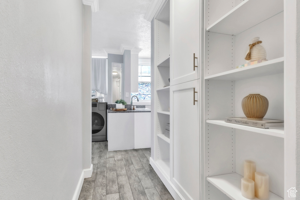 Walk in closet featuring light wood-style flooring, washer / dryer, and a sink