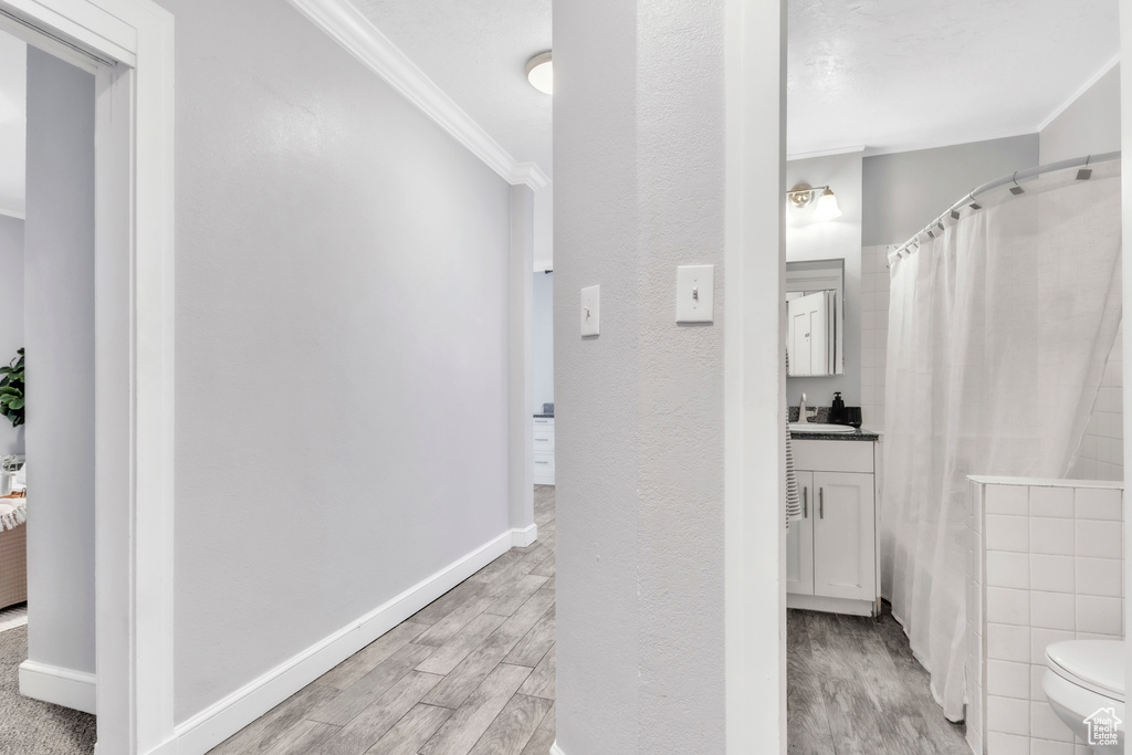 Bathroom with crown molding, wood finished floors, vanity, toilet, and baseboards