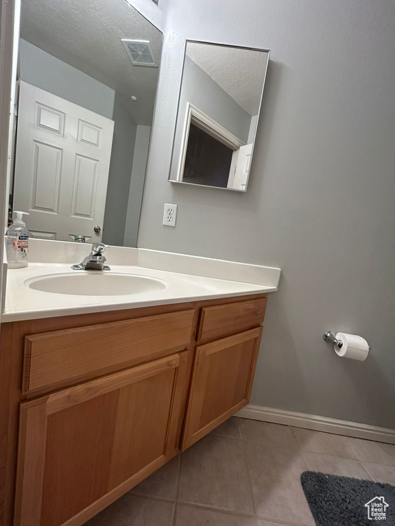 Bathroom featuring tile patterned flooring, vanity, and baseboards