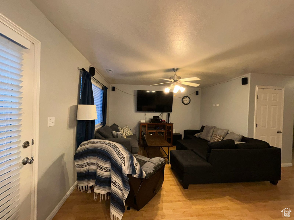 Living room featuring a ceiling fan, light wood-type flooring, and baseboards