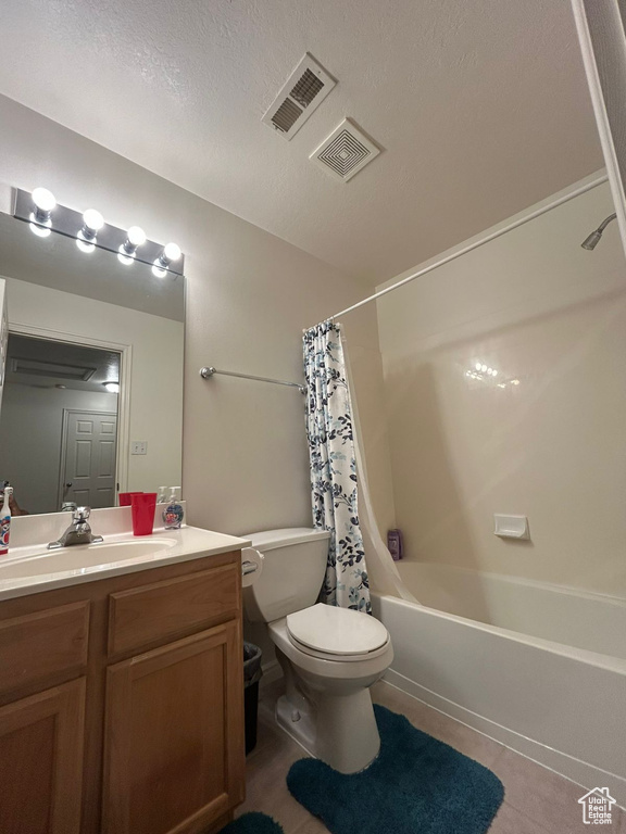 Full bath featuring toilet, tile patterned flooring, vanity, shower / bath combination with curtain, and a textured ceiling