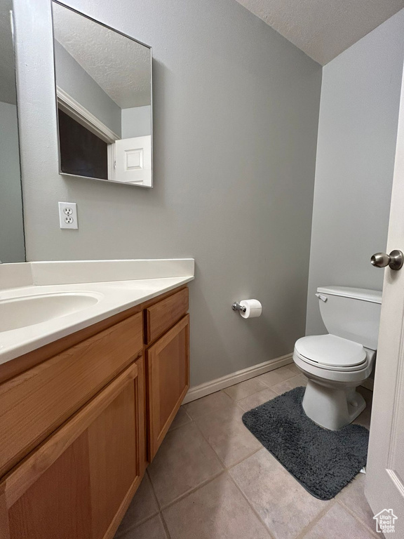 Bathroom with toilet, vanity, tile patterned floors, a textured ceiling, and baseboards