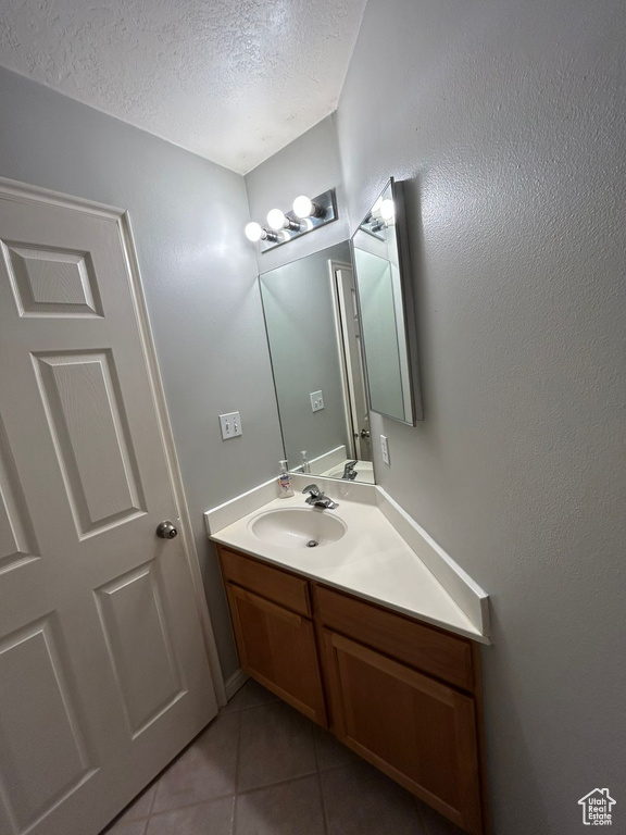 Bathroom featuring a textured ceiling, tile patterned floors, and vanity