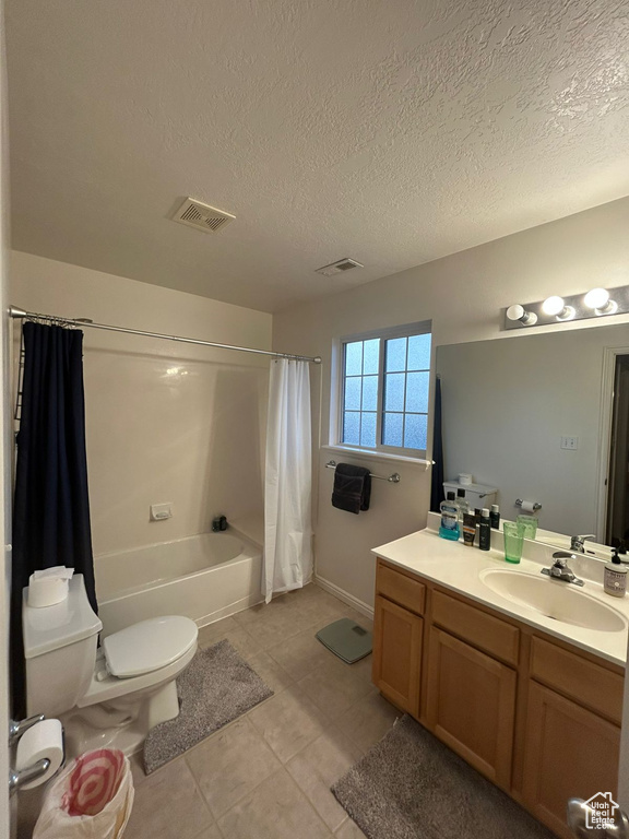 Bathroom featuring toilet, vanity, shower / tub combo, tile patterned flooring, and a textured ceiling