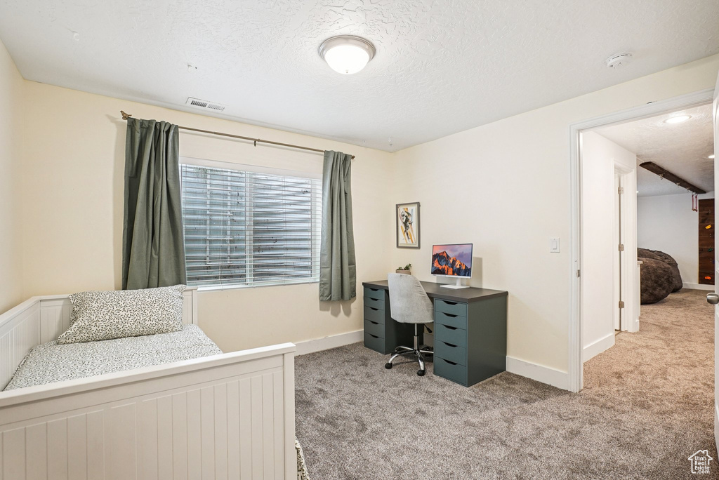 Bedroom with carpet flooring, a desk, and a textured ceiling