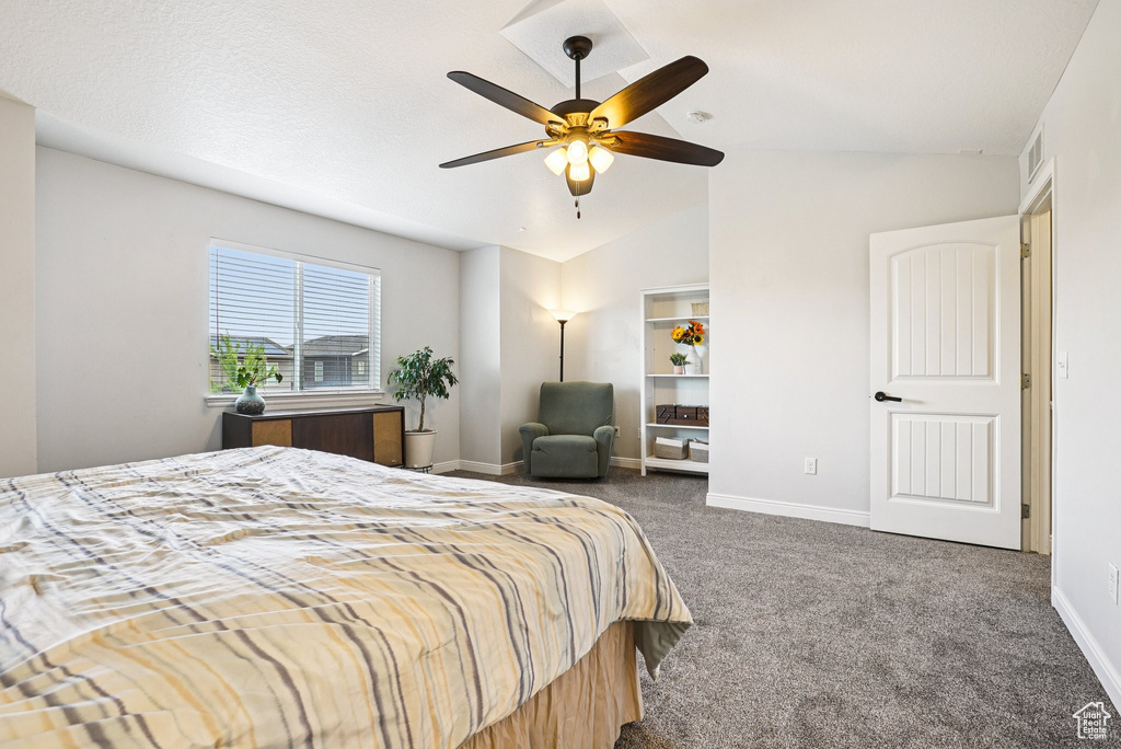 Bedroom with dark carpet, vaulted ceiling, and ceiling fan