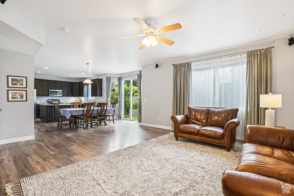 Living room with dark wood-type flooring, ceiling fan, and recessed lighting