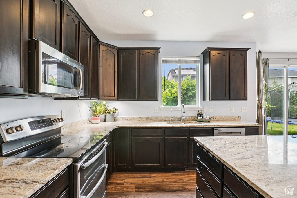 Kitchen with stainless steel appliances, dark wood-style floors, healthy amount of natural light, light stone counters, and recessed lighting