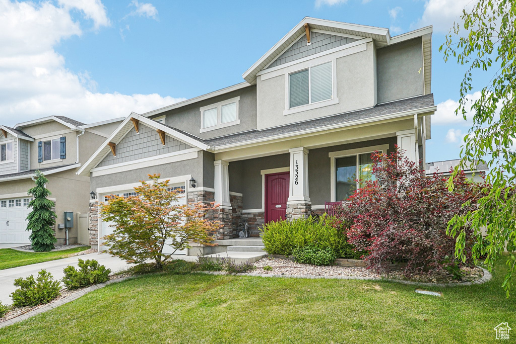 Craftsman house with stucco siding, a garage, covered porch, driveway, and a front yard